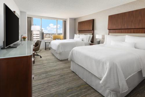a hotel room with two beds and a flat screen tv at The Westin Long Beach in Long Beach