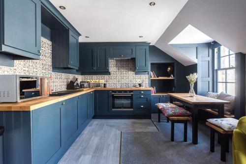 a kitchen with blue cabinets and a wooden table at Warden's Close Apartments in Edinburgh