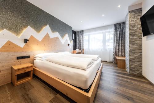 a bedroom with a large bed and a wall with mountains at CHALET ARIA Stay Mountain Relax in Arabba