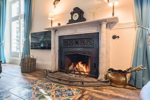 a living room with a fireplace with a clock on top at Artist's Studio in Piddlehinton