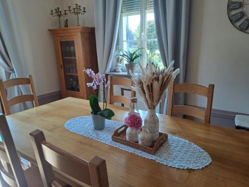 - une table à manger avec des vases et des fleurs dans l'établissement LA Maison DE CARO, à Houdelaincourt