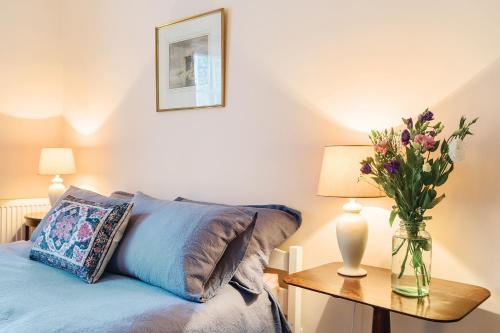 a bedroom with a bed with a vase of flowers on a table at Artist's Studio in Piddlehinton