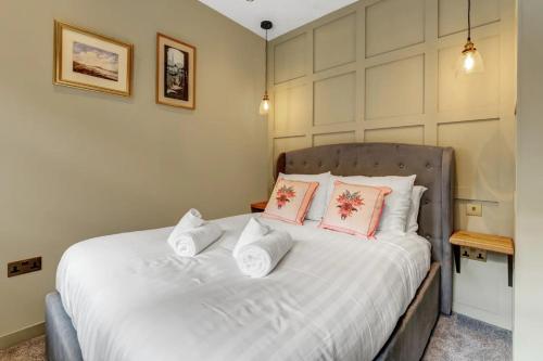 a bedroom with a bed with white sheets and pink pillows at Warden's Close Apartments in Edinburgh