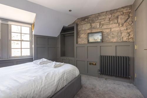 a bedroom with a large bed and a stone wall at Warden's Close Apartments in Edinburgh