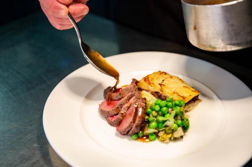 a plate of food with a piece of meat and peas at The Dowans Hotel of Speyside in Aberlour