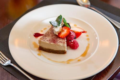 a white plate with a piece of cake and strawberries at The Dowans Hotel of Speyside in Aberlour