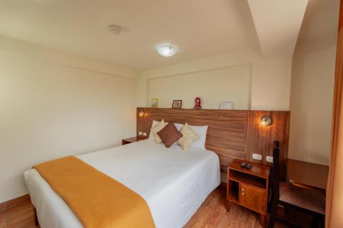 a bedroom with a large white bed with a wooden headboard at Dreams Boutique Hotel Cusco in Cusco
