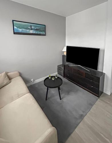 un salon avec un canapé et une télévision à écran plat dans l'établissement T2 Cuisine équipée, Parking privé, 4 personnes, à Bayeux