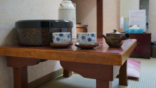 einen Tisch mit zwei Tassen und einem Topf darauf. in der Unterkunft Asakusa Ryokan Toukaisou in Tokio