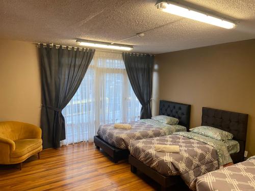a bedroom with two beds and a chair and a window at Blue house La Floresta in Quito