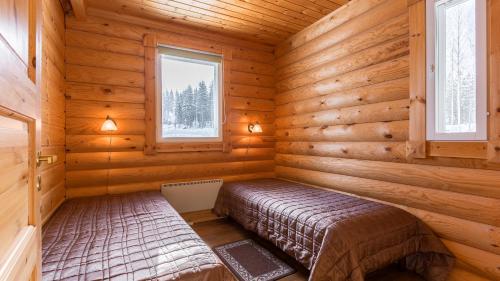 a bedroom in a log cabin with a bed and two windows at Lekotti Vacation Club in Savonranta