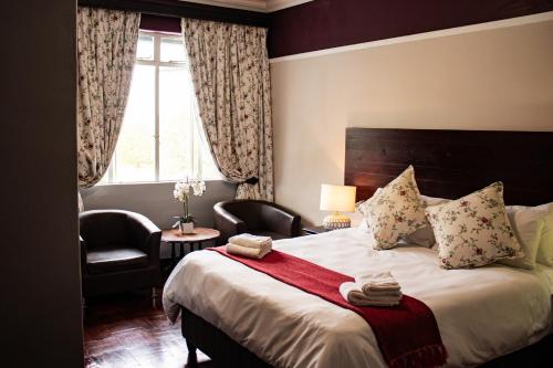 a bedroom with a bed and a chair and a window at Colenso Lodge B&B in Colenso