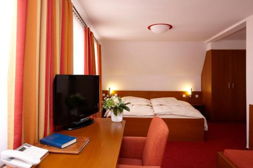 a hotel room with a bed and a desk with a television at Brauereigasthof-Hotel Roter Ochsen in Ellwangen