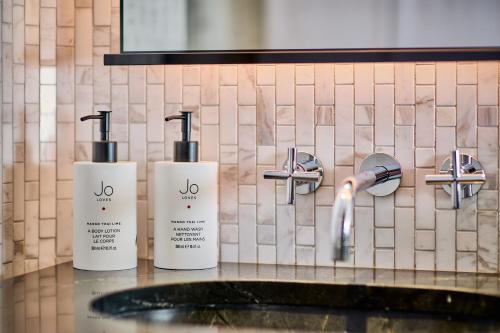 three bottles ofodorizers on a counter next to a sink at Pan Pacific London in London