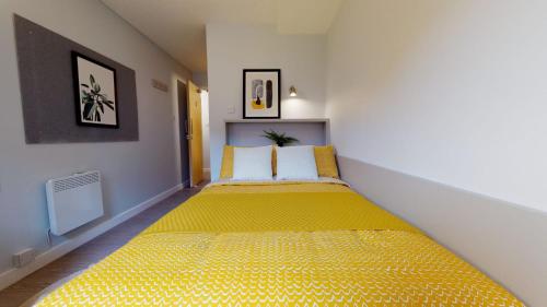 a bedroom with a yellow bed with two pillows at iQ Daisy Bank Manchester in Manchester