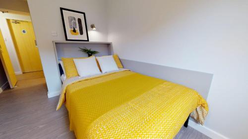 a bedroom with a bed with a yellow blanket at iQ Daisy Bank Manchester in Manchester