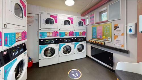 a laundry room with three washer and dryers at iQ Daisy Bank Manchester in Manchester