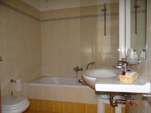 a bathroom with a tub and a sink and a toilet at Hotel Mondeval in Selva di Cadore