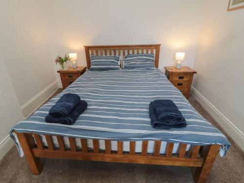 une chambre avec un lit avec deux serviettes bleues dessus dans l'établissement Riverside Cottage, à Warkworth