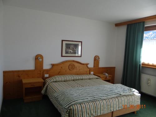 a bedroom with a bed with a wooden headboard and a window at Hotel Mondeval in Selva di Cadore