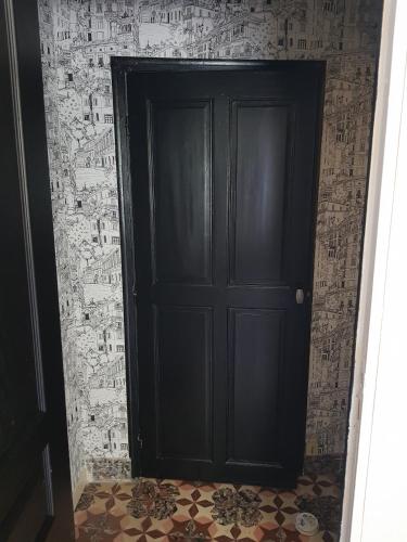 - une porte noire dans une chambre avec papier peint dans l'établissement La Riviere, à Avène
