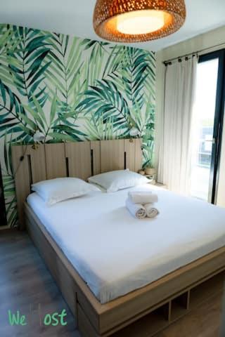 - une chambre avec un lit blanc et un papier peint tropical dans l'établissement Guynemer-Saint-Cyr-L'école - CI - Le Trianon