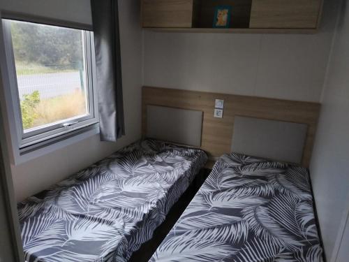 deux lits dans une petite pièce avec une fenêtre dans l'établissement mobil home siblu, aux Mathes