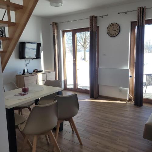 a dining room with a table and chairs and a clock at Domek Pod Lasem in Czarny Dunajec