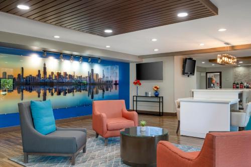 a lobby with chairs and a painting of a city at Best Western Plus Lafayette Hotel University Area in Lafayette