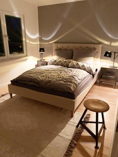a bedroom with a bed and a stool and two windows at Mastenkieker in Kappeln