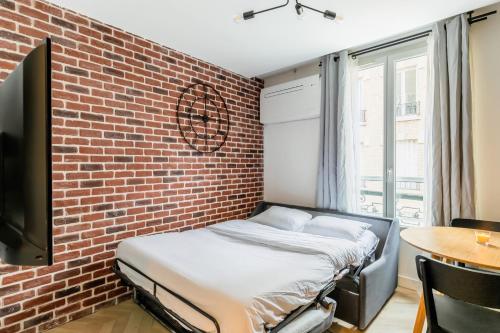 un lit dans une chambre avec un mur de briques dans l'établissement unwind in timeless comfort, à Paris