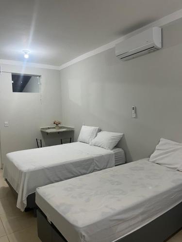 two beds in a white room with a table at Studio 38 - Próx ao Parque do Sabiá Aeroporto e Shopping in Uberlândia