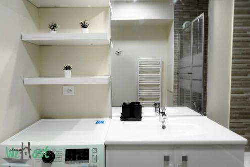 une salle de bain blanche avec un lavabo et un miroir dans l'établissement Guynemer-Saint-Cyr-L'école - CI - Le Trianon