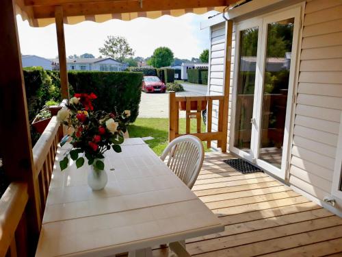 un porche en bois avec une table et un vase de fleurs dans l'établissement Large 2 bedroom mobile home Cc441 Siblu Les Charmettes, aux Mathes