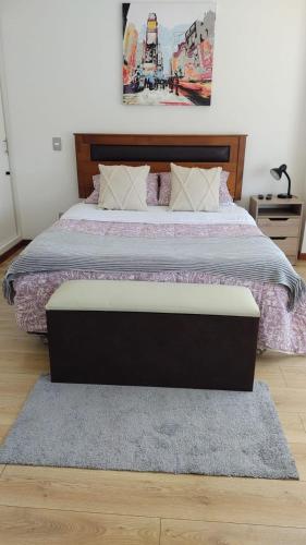 a bedroom with a large bed with a wooden headboard at Departamento Los Carrera Centro in Osorno