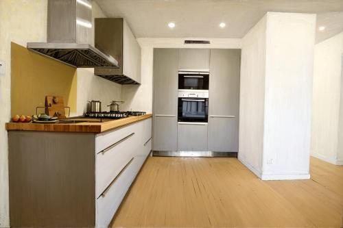 une cuisine avec des armoires blanches et un four à plaques de cuisson dans l'établissement Strasbourg bel appartement gare, à Strasbourg