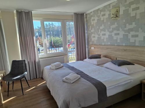 a bedroom with a bed and a chair and a window at Wodnik Turawa in Turawa
