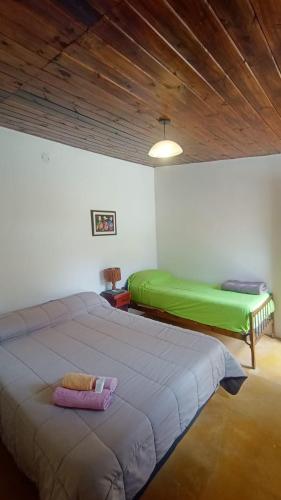 a bedroom with two beds and a wooden ceiling at Hostal La Albahaca in Tilcara