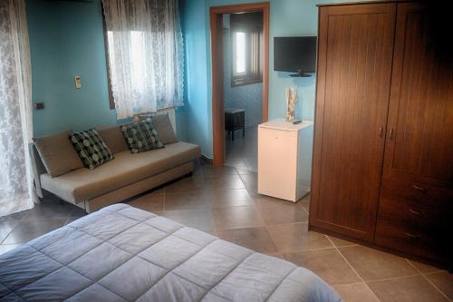 sypialnia z łóżkiem, kanapą i telewizorem w obiekcie B&B Terrazza dell'Etna w mieście Mascalucia