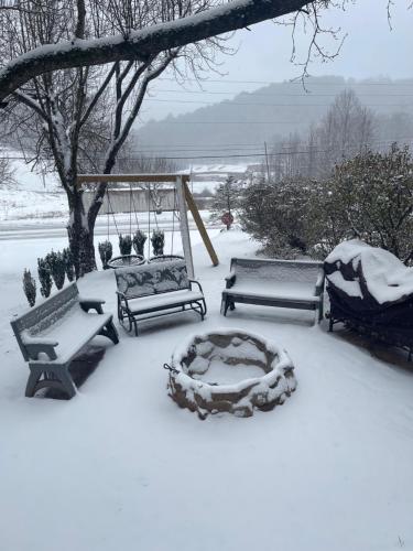 a snow covered yard with benches and a swing at Mountain Aire Cottages, Inn, & Glamping in Clayton