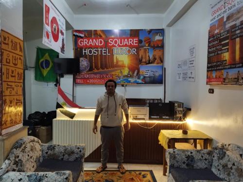 a man standing in a room with two chairs at Grand Square Hostel Luxor in Luxor