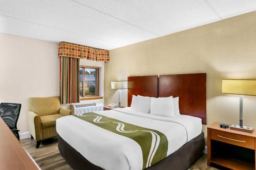 a hotel room with a large bed and a chair at Quality Inn Jessup - Columbia South Near Fort Meade in Jessup