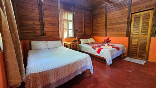 a bedroom with two beds in a wooden cabin at Cabañas Yax-ha in Arroyo Agua Azul