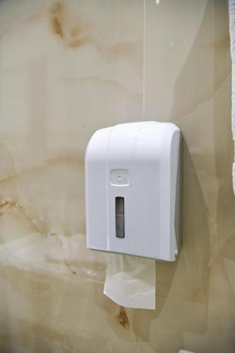 a white paper towel dispenser on a bathroom wall at Hotel Restaurant Dreri in Tirana