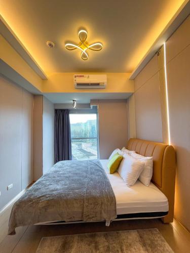 a bedroom with a bed with a ceiling fan and a window at Luxury 1BR across Okada, Solaire in Manila