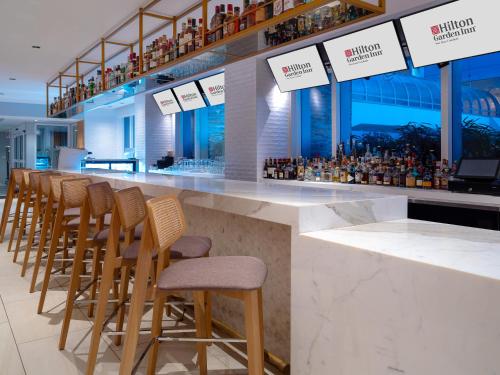 a bar with a row of wooden stools at Hilton Garden Inn San Juan Condado in San Juan