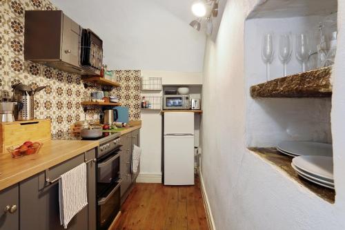 a small kitchen with stainless steel appliances and wooden floors at Waterview Cottage - a peaceful riverside location in Holmfirth