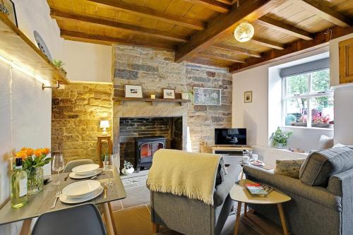 a living room with a table and a fireplace at Waterview Cottage - a peaceful riverside location in Holmfirth