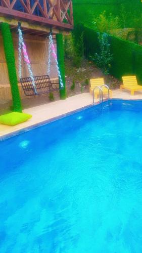 a large swimming pool with two yellow chairs and water at Şifaköy Bungalov in Sapanca