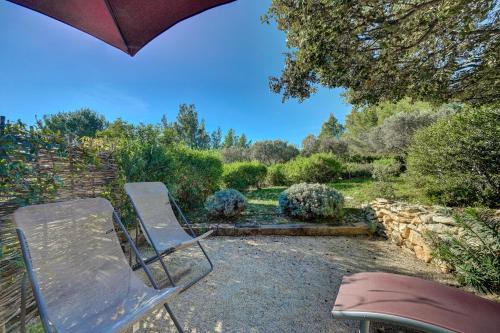 two chairs and an umbrella in a garden at Les Garrigues de la Vallée des Baux in Paradou